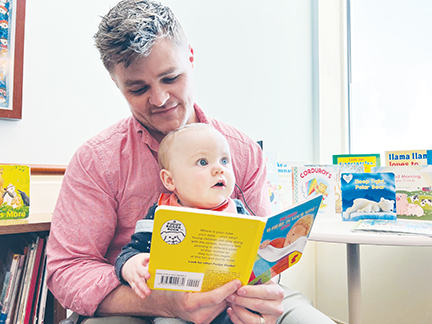 A man and his son read a book together.