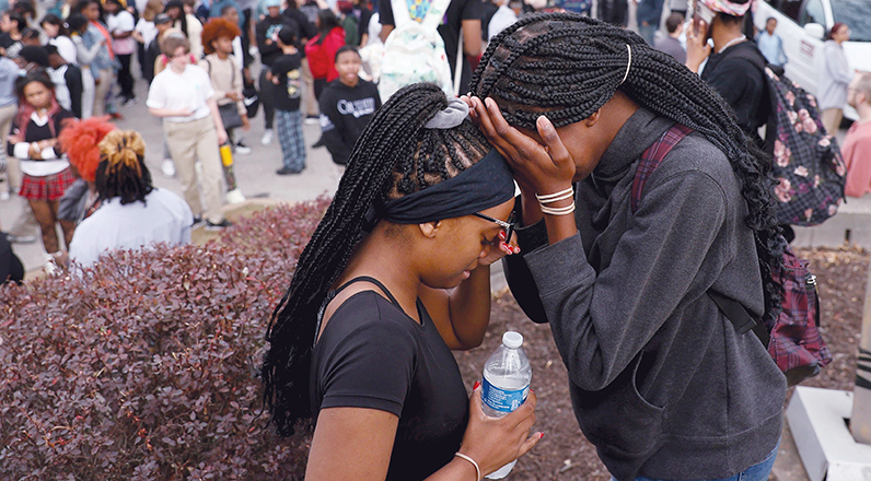 Students gather in a parking lot near St. Louis’ Central Visual and Performing Arts High School after a shooting.