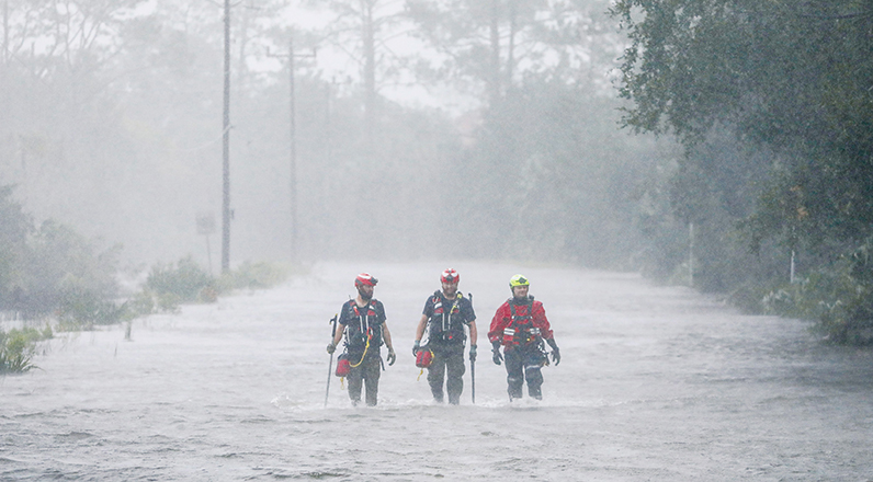 Rescue workers wade through a tidal surge on a highway.