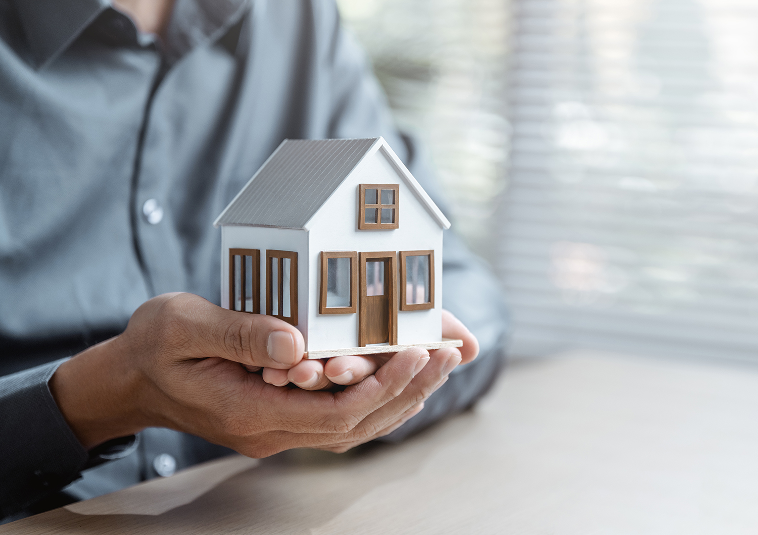 a person holding a small house display in their hand