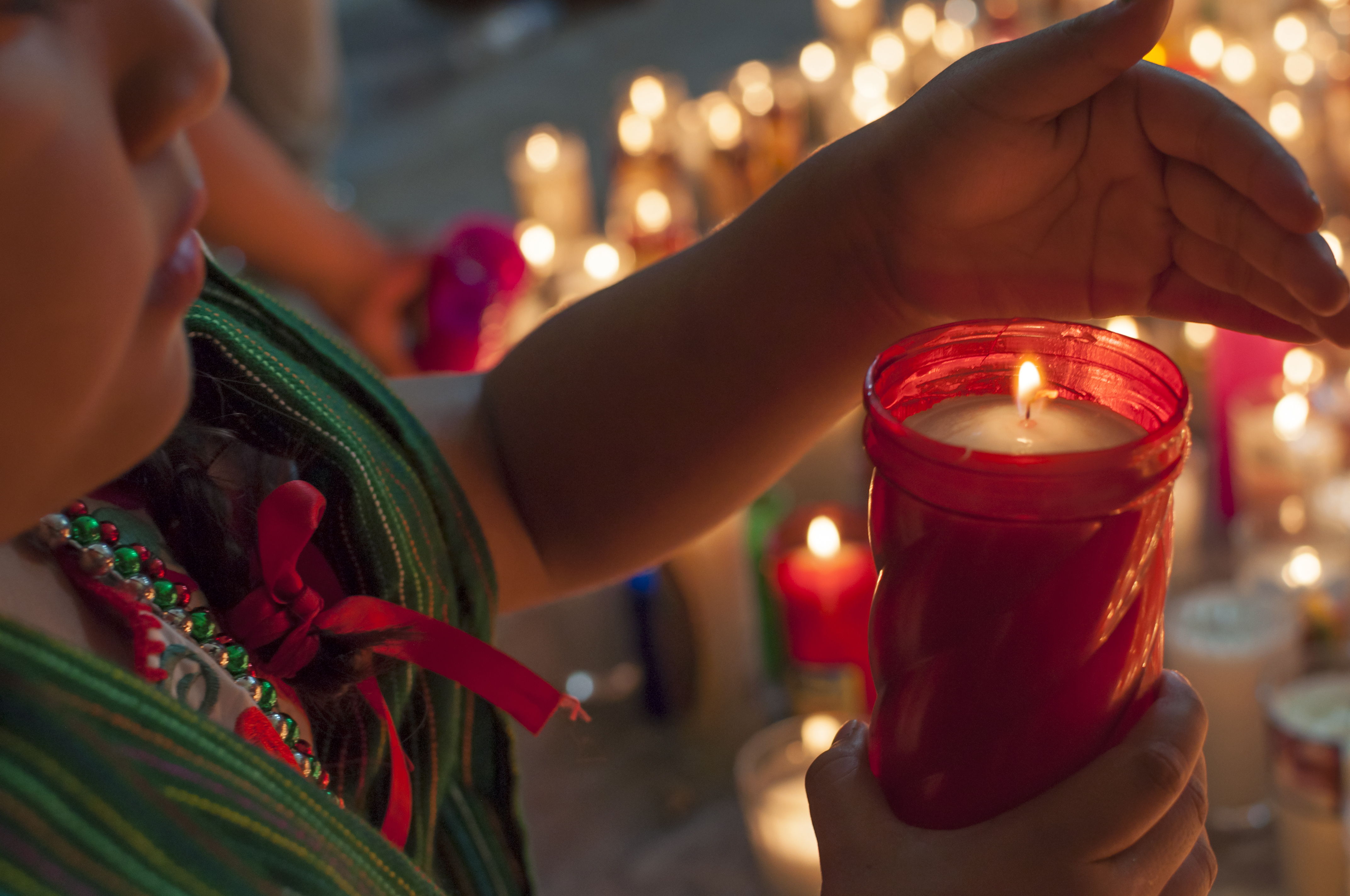 Our lady of Guadalupe girl lights candle after mass iStock-530098565